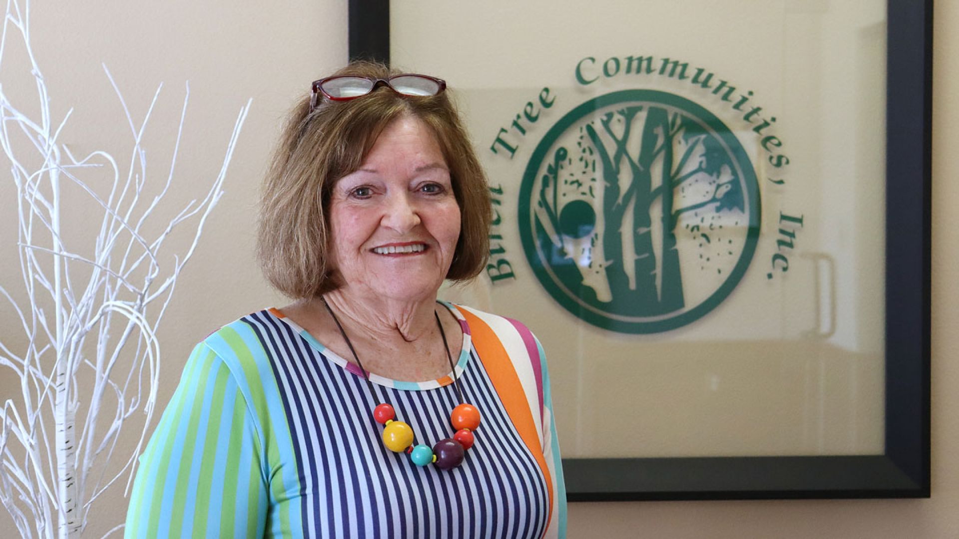 Cindy Slaughter in front of Birch Tree Communities logo sign
